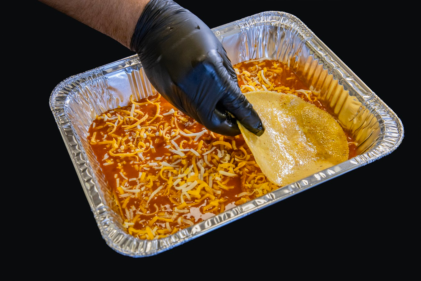 Dipping a tortilla in cheese enchilada sauce